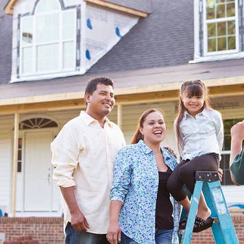 Young family posing in front of new home