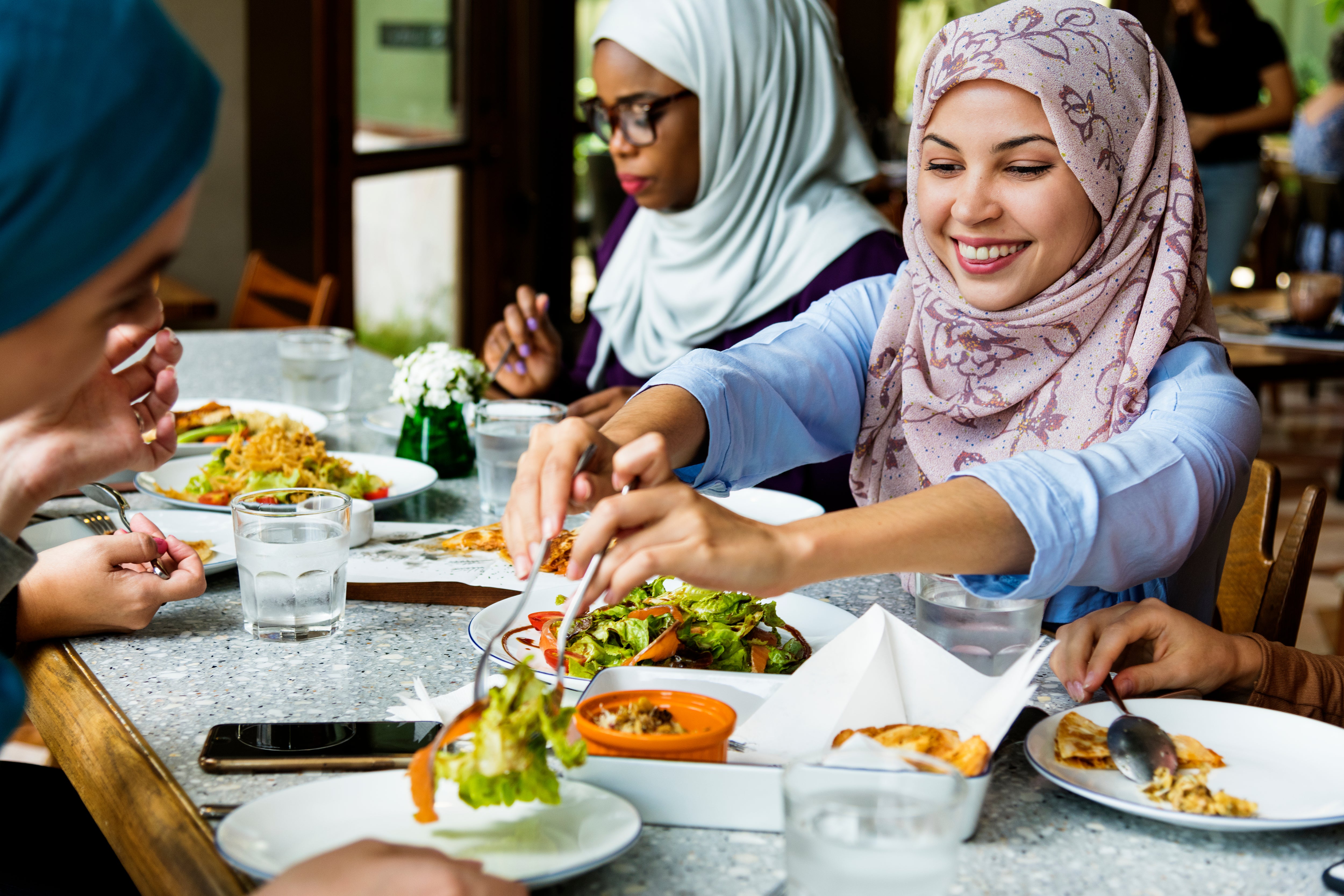 Muslim women in hijabs sharing a meal