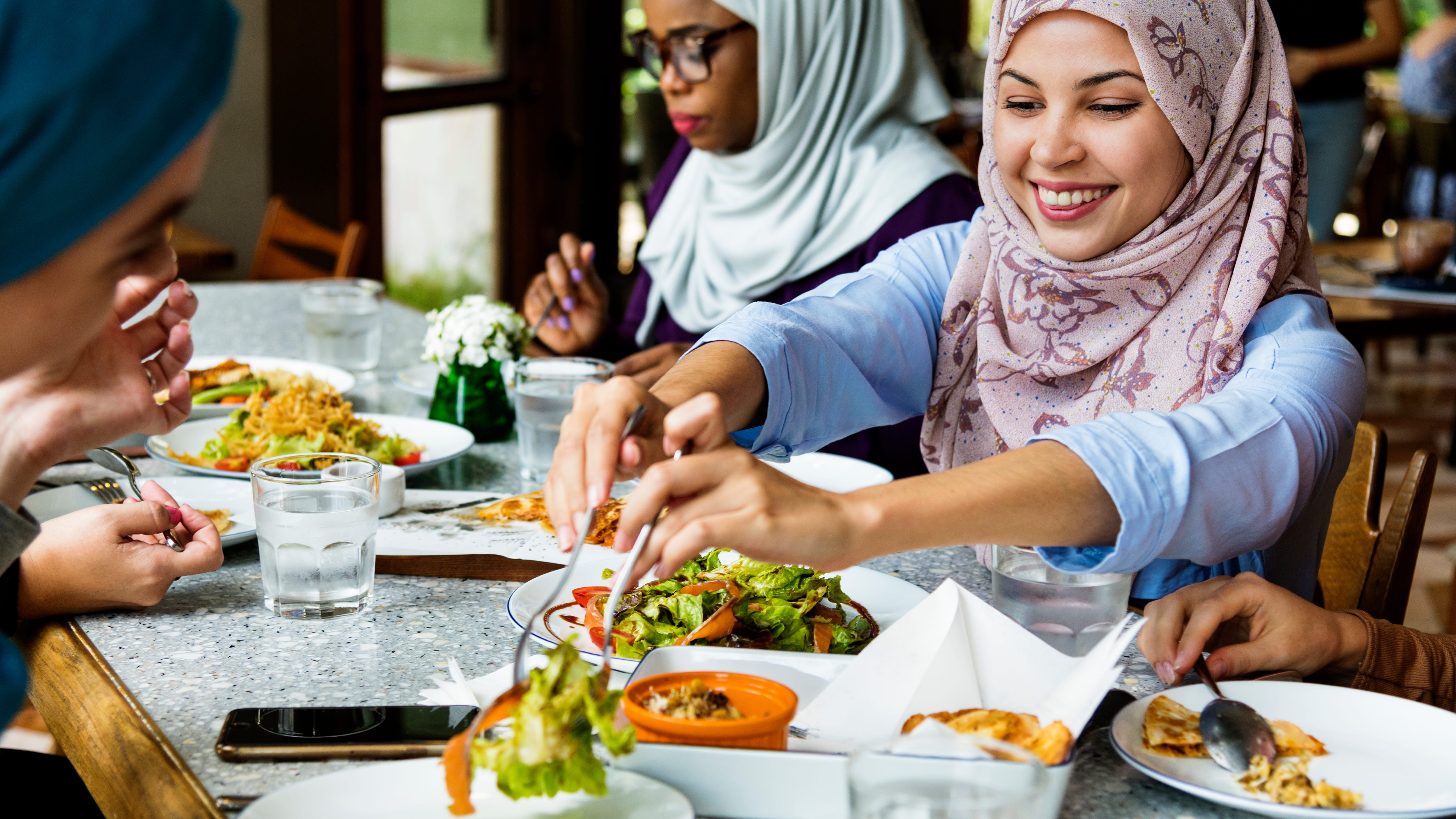 Muslim women in hijabs sharing a meal