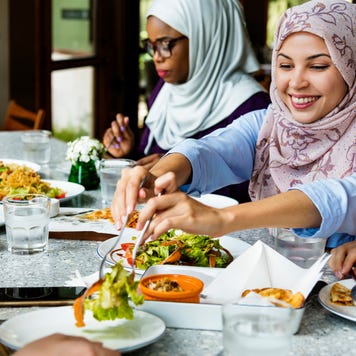 Muslim women in hijabs sharing a meal