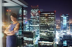 Woman looking outside of a skyscrapper window at night