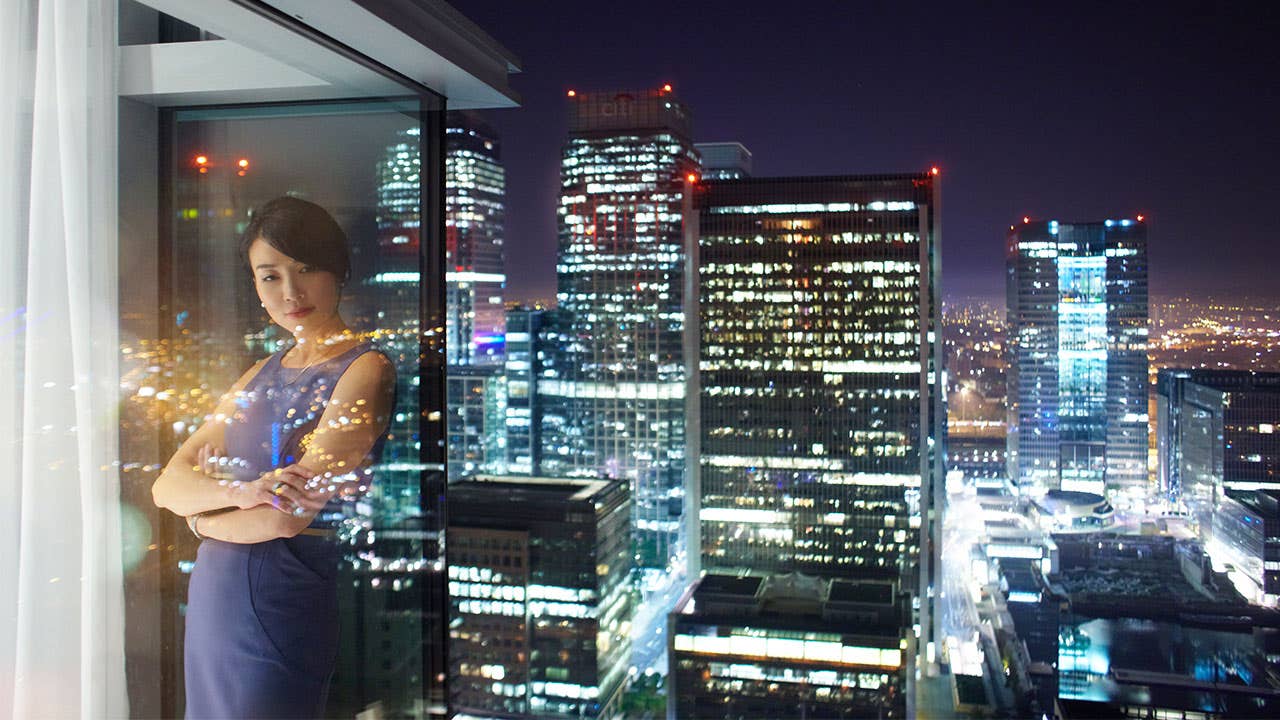 Woman looking outside of a skyscrapper window at night