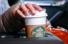 Woman reaching for coffee cup in car