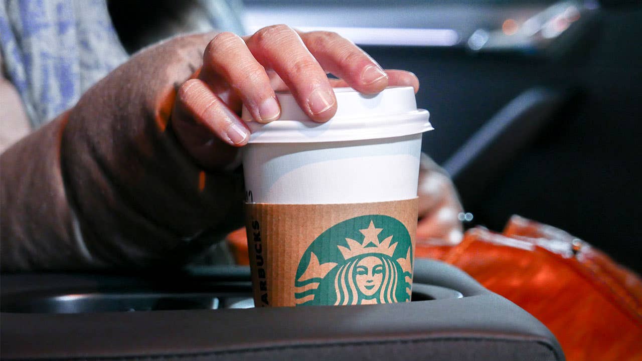 Woman reaching for coffee cup in car