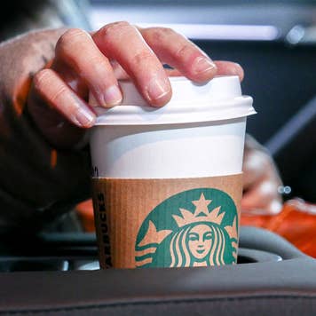 Woman reaching for coffee cup in car