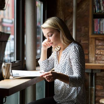 Woman in coffeeshop reviewing paperwork