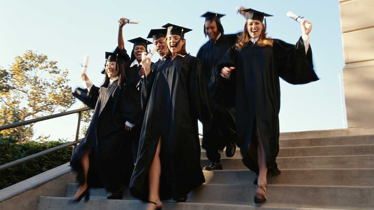 Group of excited graduates running down steps