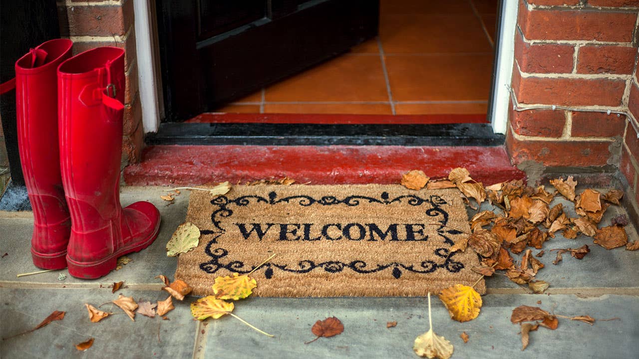 Red rain boots at front door with welcome mat