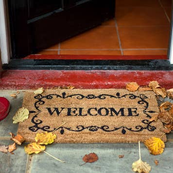 Red rain boots at front door with welcome mat