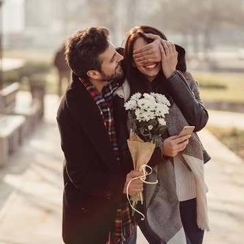 Man surprising girlfriend with flowers