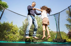 Father and daughter bouncing on trampoline