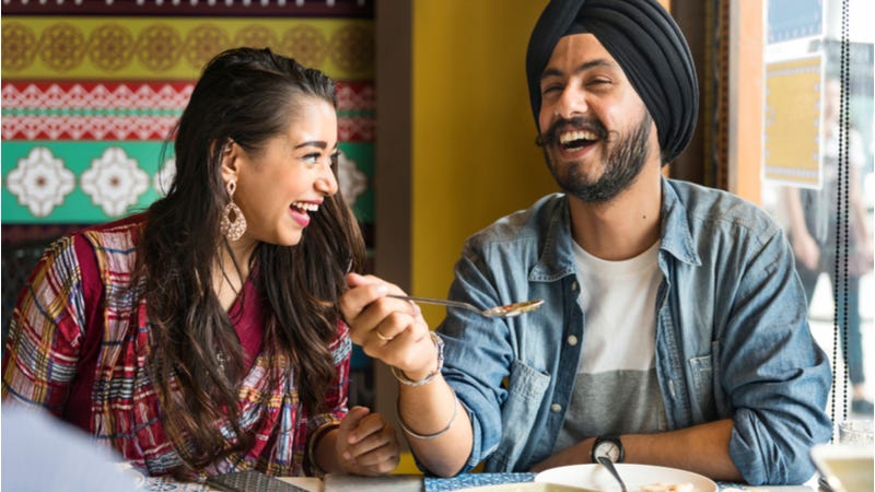 Young Indian couple laughing over meal