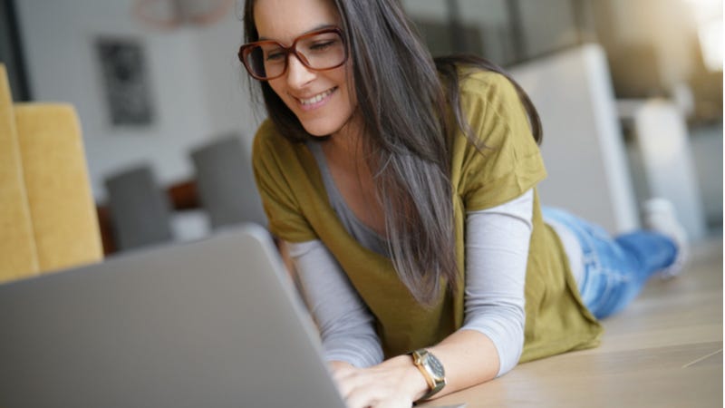 Young woman laying on ground working on laptop