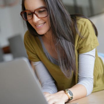 Young woman laying on ground working on laptop