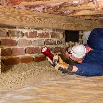 Home inspector looking under insulation