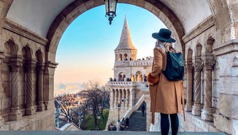 Woman looking out over steps of historic building in Budapest