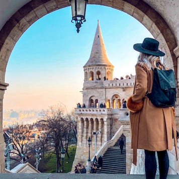 Woman looking out over steps of historic building in Budapest