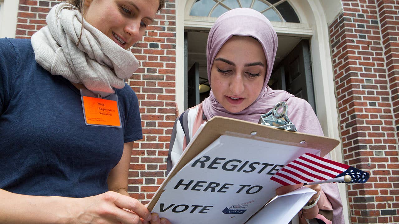 A new American citizen, originally from Iraq, registers to vote immediately after a naturalization ceremony in Faneuil Hall, on June 7, 2018 in Cambridge, Massachusetts. More than 300 people became Americans.