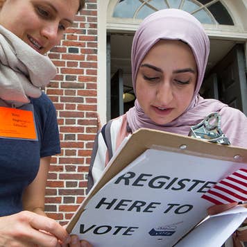 A new American citizen, originally from Iraq, registers to vote immediately after a naturalization ceremony in Faneuil Hall, on June 7, 2018 in Cambridge, Massachusetts. More than 300 people became Americans.