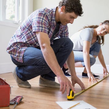 Couple measuring a hardwood floor