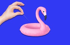 Woman with needle puncturing a flamingo floaty