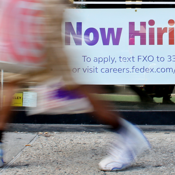 A "Now Hiring" sign is displayed on a shopfront