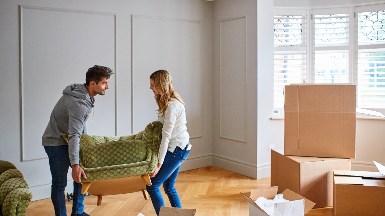 A couple moving furniture into a house.