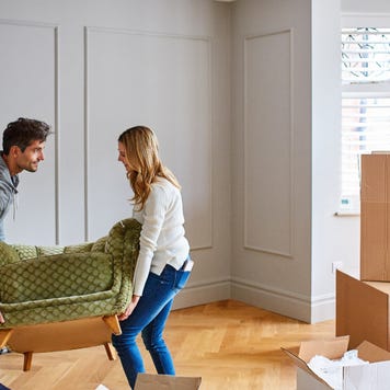 A couple moving furniture into a house.
