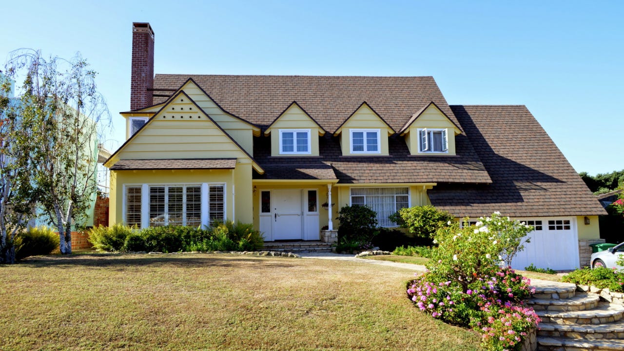 A picture of a large yellow house with three gables