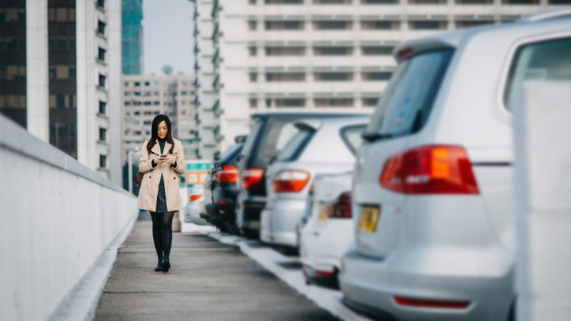 woman texting next to a row of cars