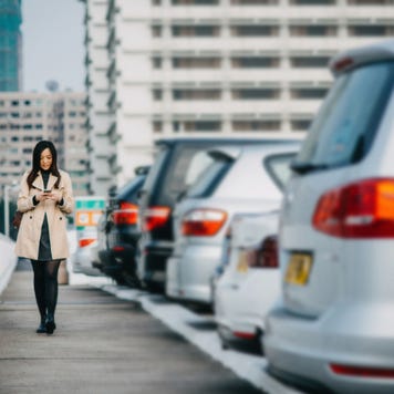 woman texting next to a row of cars