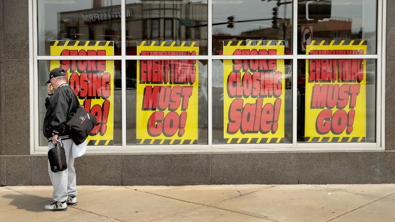Signs in the window of a Sears store advertise its closing.