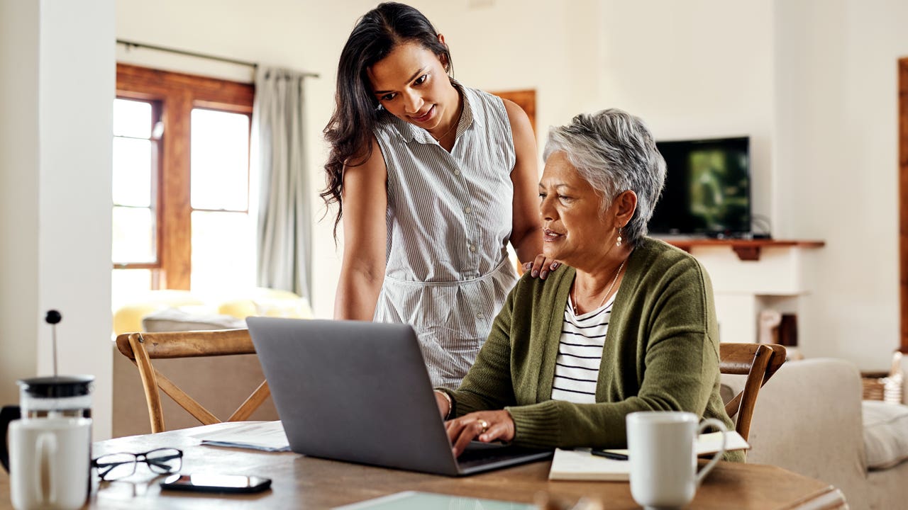 mother and adult daughter working on laptop at home