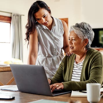mother and adult daughter working on laptop at home