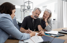 Financial advisor discussing paperwork with senior couple at dining table