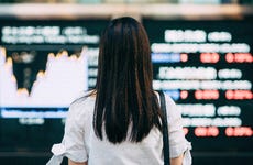 Woman looking at stock exchange market display screen