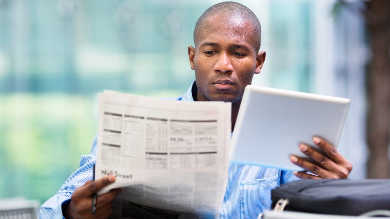 A man studies the Wall Street Journal and considers placing a trade