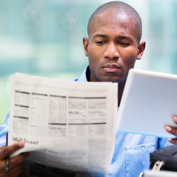 A man studies the Wall Street Journal and considers placing a trade