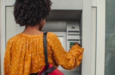 back view of woman using an outdoor atm