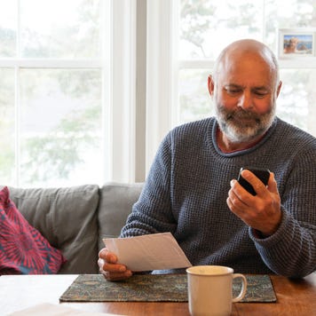 A mature, mixed race man dealing with finances and bills at home in his dining room. Photographed in North America
