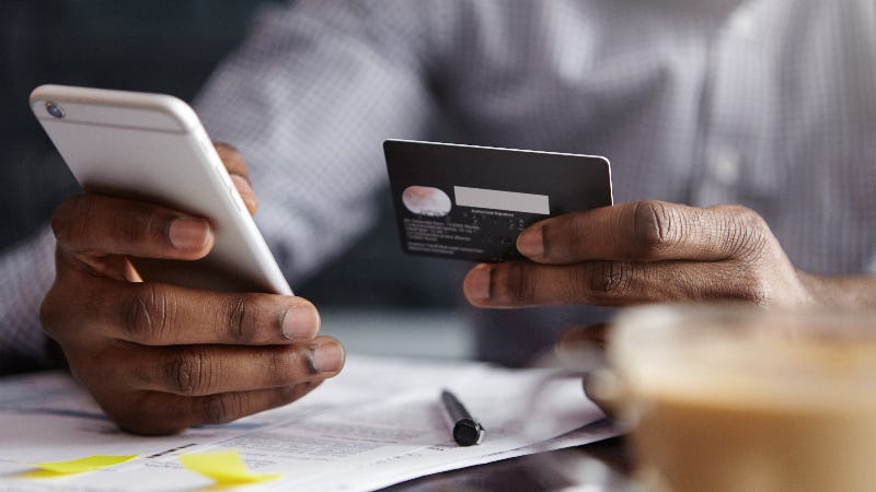 man holding credit card in one hand and phone in the other