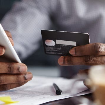man holding credit card in one hand and phone in the other
