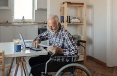 Disabled Senior Man in a Wheelchair Working From Home