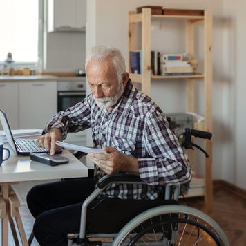 Disabled Senior Man in a Wheelchair Working From Home
