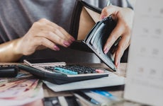 woman at desk with open wallet, calculator and papers
