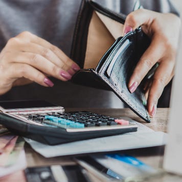 woman at desk with open wallet, calculator and papers