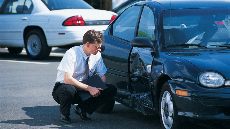 man inspecting damaged car