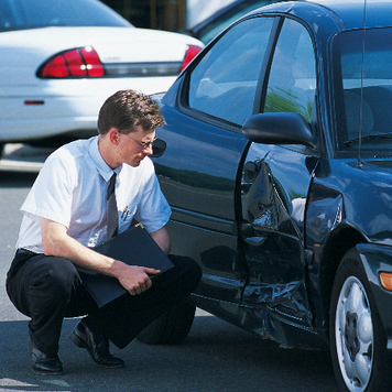man inspecting damaged car