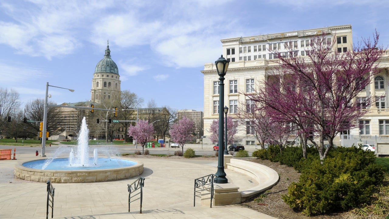 Shot of Topeka, Kansas with buildings in the distance and an ornate fountain in the middle.