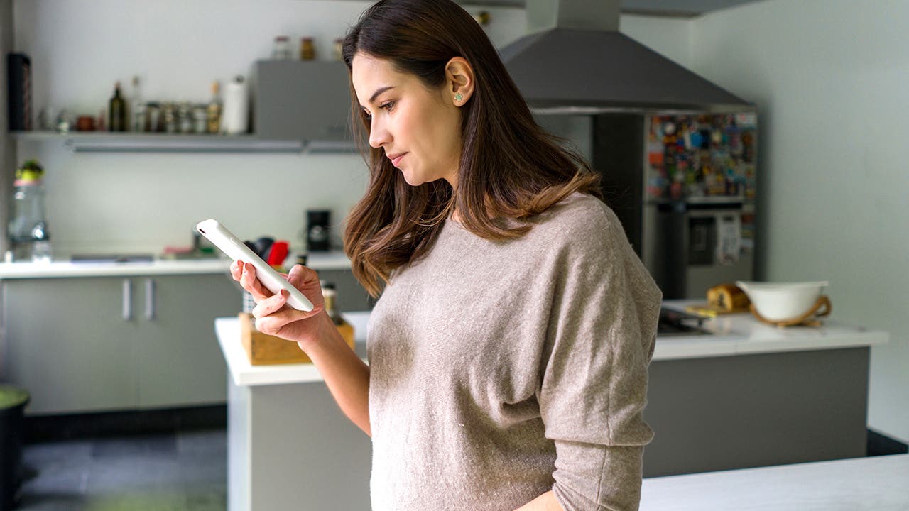 pregnant woman at home looking at phone